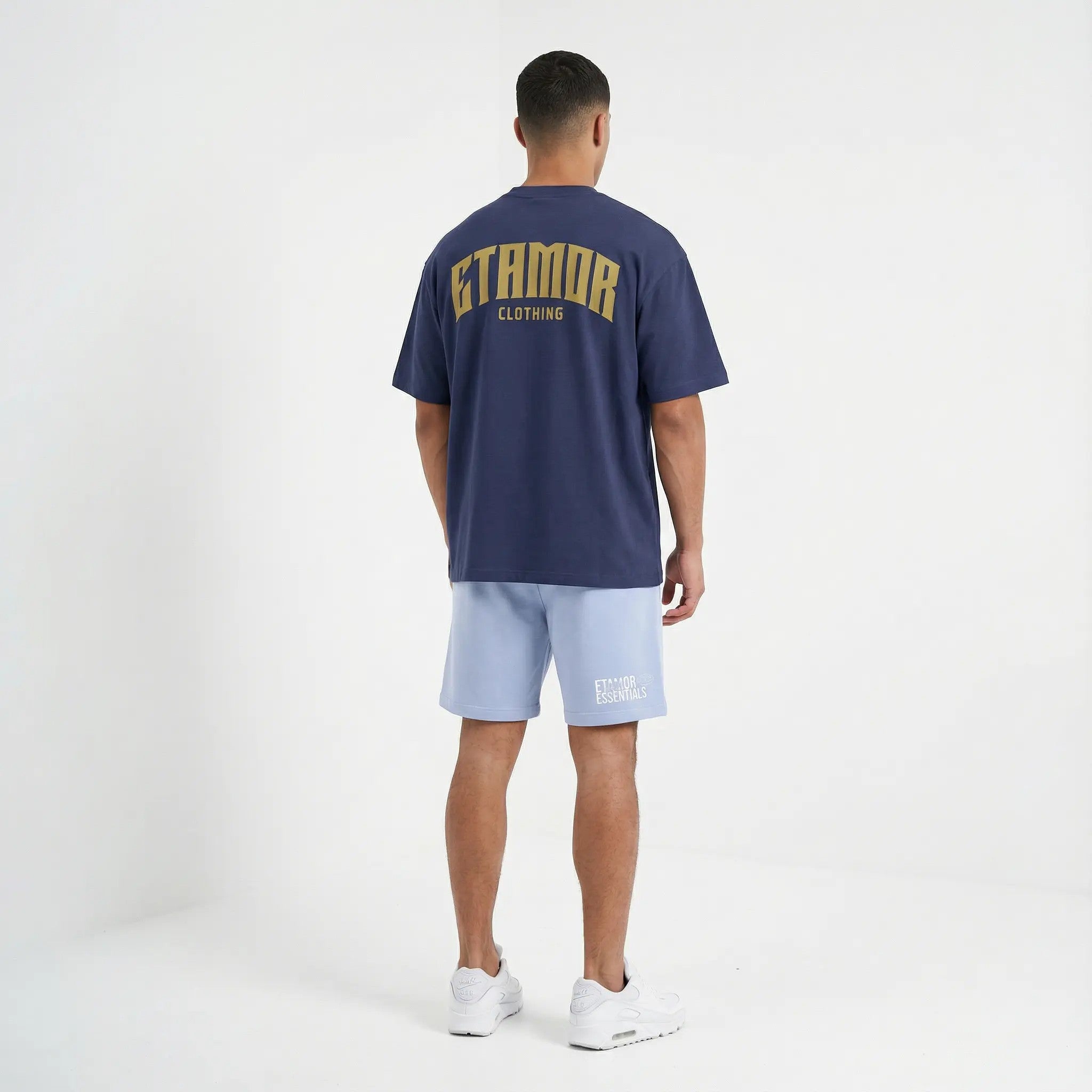 Person wearing a navy blue t-shirt with 'ETAMOR CLOTHING' branding on the back, standing against a white background.