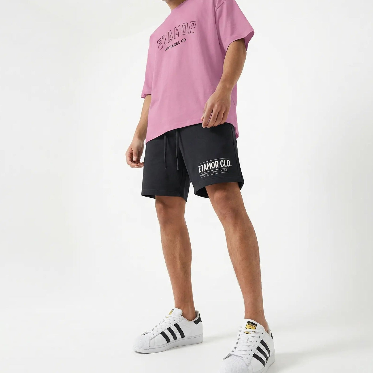 Person wearing a pink t-shirt, black shorts, and white sneakers on a white background